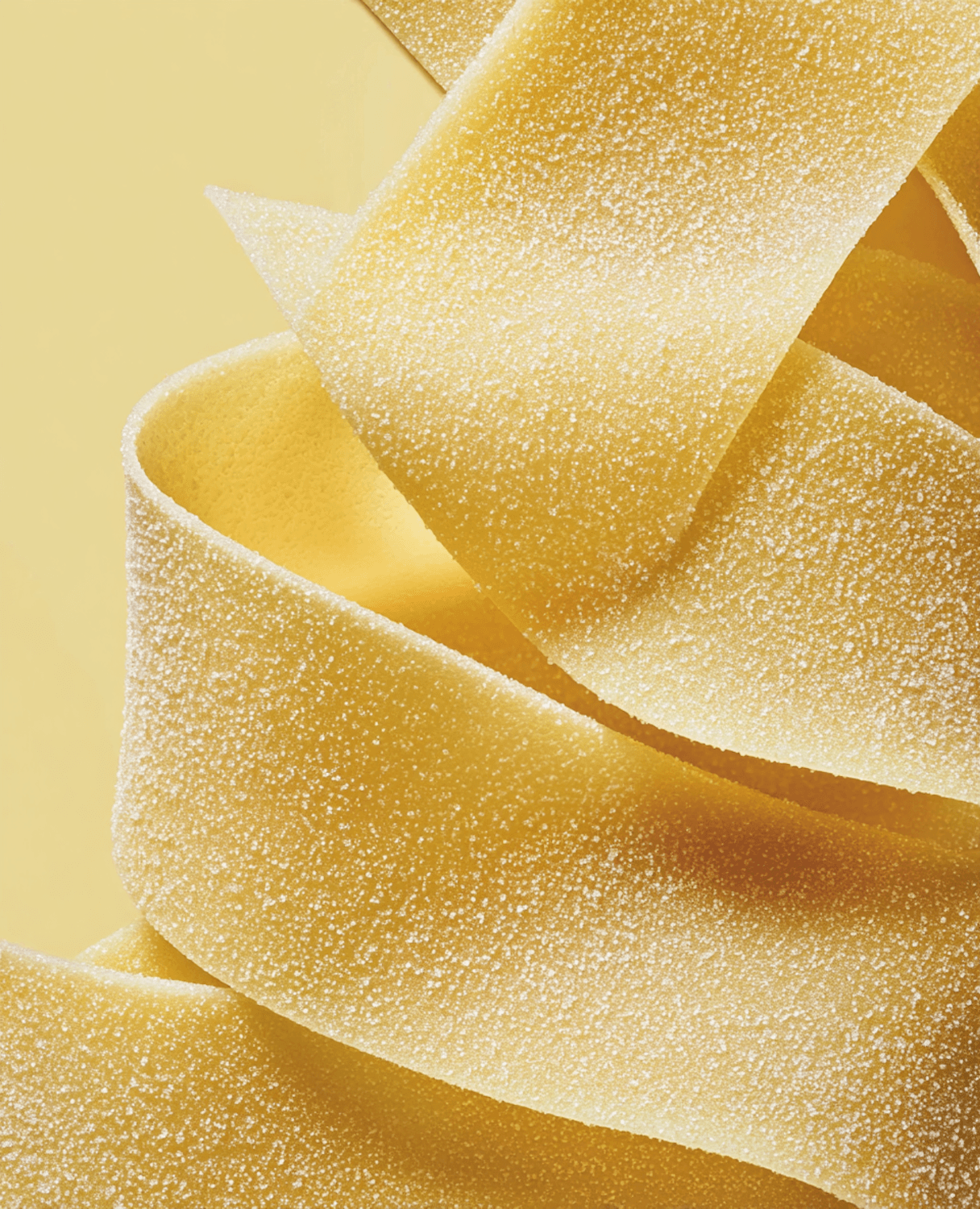 Cintas de pappardelle fresco espolvoreadas con harina sobre la mesa de trabajo.